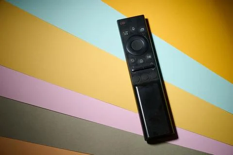 Close-up of a television remote control resting on a colourful surface. Stock Photos