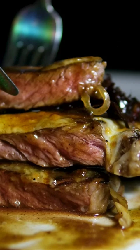 Close-up of a tender beef steak being picked up by a fork, revealing juicy Stock Footage 323926176