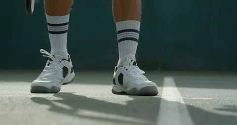 Close up of a Tennis Player serving as he jumps out of shot. Video stock 115974663