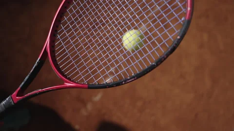 Close-up of tennis racket hitting a yellow tennis ball on a clay court in slow 库存影片 288017774