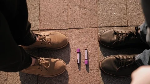 Close-up of test tube with a blood test for coronavirus and the shoes of people. Stock Footage 128317757
