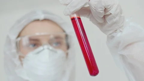 Close-up of a test tube with a red solution, which the doctor holds over her. A Stock Footage 124783691