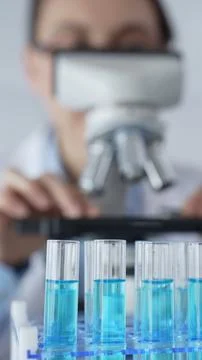 Close up of test tubes with blue liquid while scientist focusing on analyzing Stock Photos