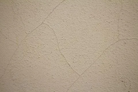 Close-up texture of beige plaster wall with fine cracks and rough surface Stock Photos