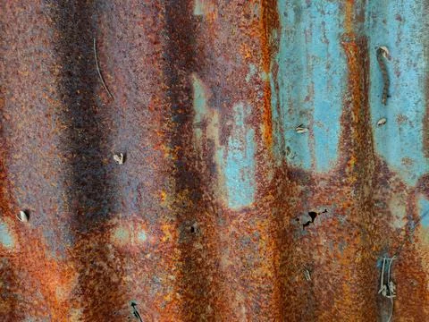 A close-up texture of a corrugated metal sheet covered in heavy orange rust.. Stock Photos