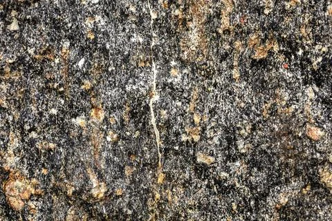 Close-up texture of dark granite with flecks of white and orange minerals Stock Photos