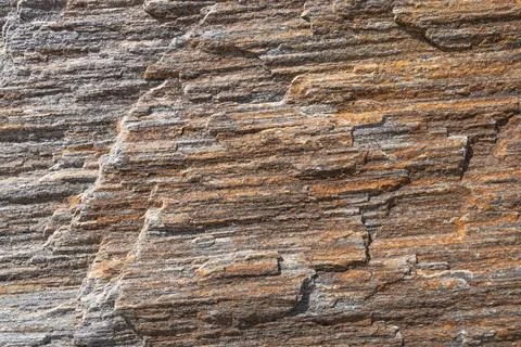 A close-up texture of a layered, weathered rock formation with varying shades Stock Photos