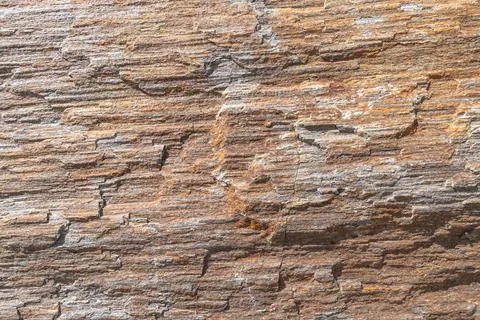 A close-up texture of a layered, weathered rock formation with varying shades Stock Photos