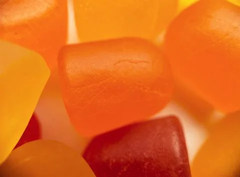 Close-up texture of orange and yellow multivitamin gummies on white background Stock Photos