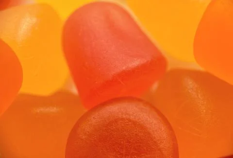 Close-up texture of orange and yellow multivitamin gummies on white background Stock Photos