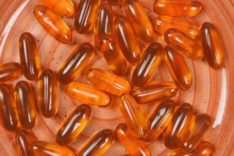 Close up texture of orange liquid gel capsules on an orange ceramic plate Stock Photos