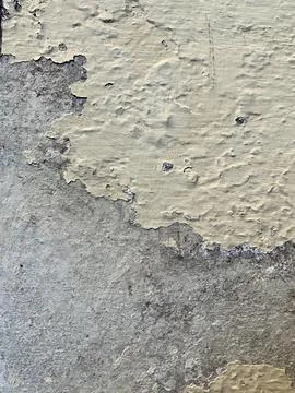 Close up texture of peeling old beige paint on a weathered concrete wall surface Stock Photos