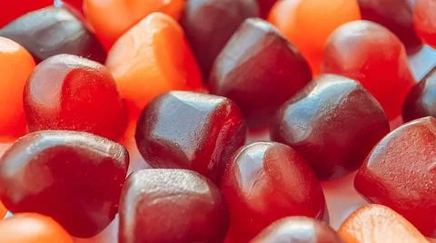 Close-up texture of red, orange and purple multivitamin gummies on white Stock Photos