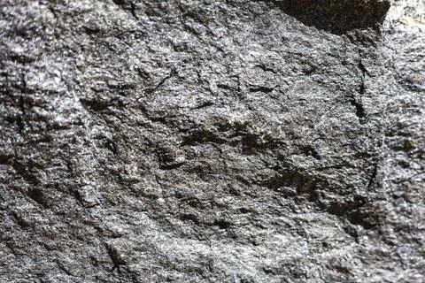 Close-up texture of a rough, dark gray granite rock surface with sparkling .. Stock Photos