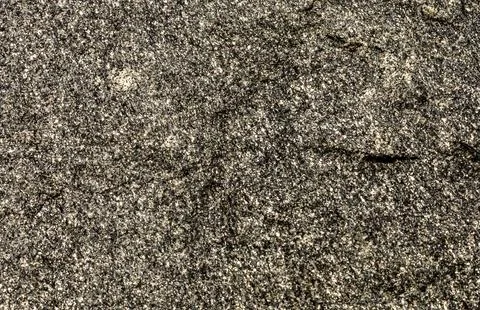 Close-up texture of a speckled granite rock surface with visible mineral grai Stock Photos
