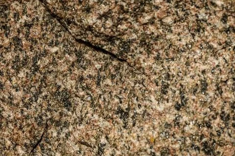 Close-up texture of speckled granite rock with a natural crack Stock Photos