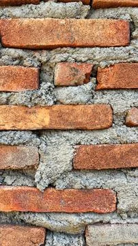 Close-up texture of a traditional red brick wall with rough cement mortar joints 库存照片