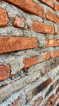 Close-up texture of a traditional red brick wall with rough cement mortar joints Foto stock