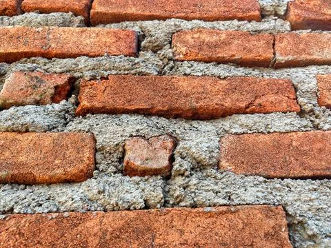 Close-up texture of a traditional red brick wall with rough cement mortar joints Foto stock