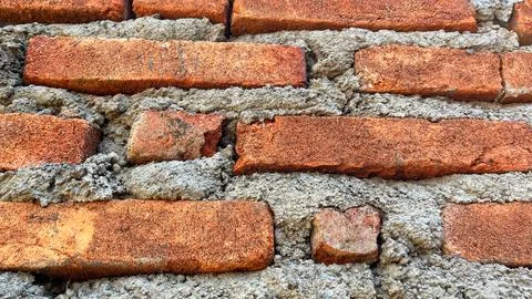 Close-up texture of a traditional red brick wall with rough cement mortar joints Foto stock