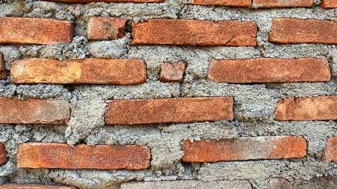 Close-up texture of a traditional red brick wall with rough cement mortar joints Stock-Fotos