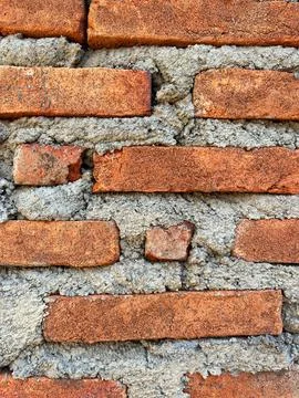 Close-up texture of a traditional red brick wall with rough cement mortar joints Stock Photos