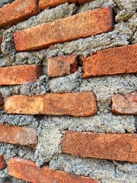 Close-up texture of a traditional red brick wall with rough cement mortar joints Foto stock