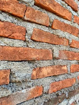 Close-up texture of a traditional red brick wall with rough cement mortar joints Foto stock