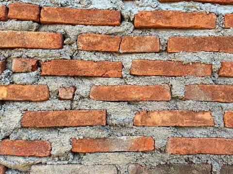 Close-up texture of a traditional red brick wall with rough cement mortar joints Foto stock