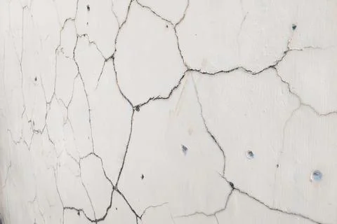 Close-up texture of a white cracked wall with visible lines and aged surfac.. Фото