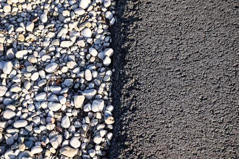 Close-Up Texture of White Pebbles and Dark Asphalt at Construction Site Border Foto stock