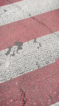 Close-up texture of a worn red and white zebra pedestrian crossing on a cra.. Foto stock