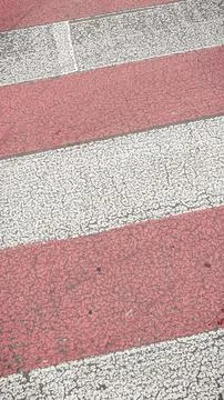 Close-up texture of a worn red and white zebra pedestrian crossing on a cra.. Foto stock