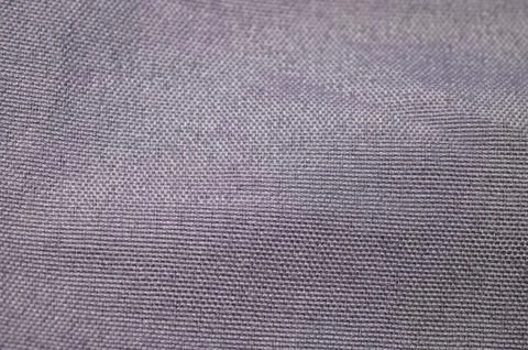 Close-up texture of a woven fabric with a subtle purple hue and visible threa Stock Photos