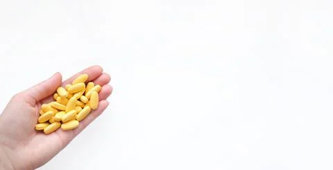 Close-up texture of yellow multivitamin tablets in female hand on white Stock Photos