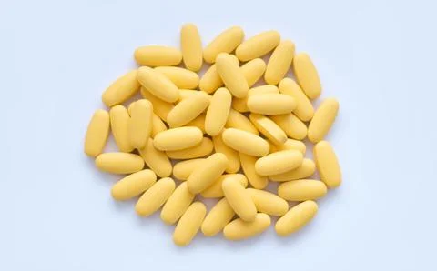Close-up texture of yellow multivitamin tablets on white background. Healthy Stock Photos