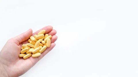 Close-up texture of yellow multivitamin tablets in female hand on white Stock Photos