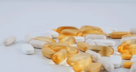 Close-up texture of yellow tablets, white capsules lying white background Stock Footage 126340549