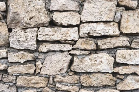 Close-up textured background is an irregular natural stone wall made of Stock Photos