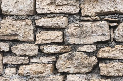 Close-up textured background is an irregular natural stone wall made of Stock Photos