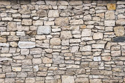Close-up textured background is an irregular natural stone wall made of Stock Photos