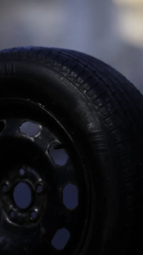 Close up of a textured black tire mounted on a sturdy wheel in natural light Stock Footage 331811581