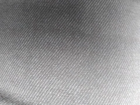 Close-up of a textured gray fabric with a diagonal weave pattern. Stock Photos