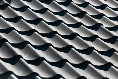 Close-up of textured gray wavy tile roof pattern in sunlight Stock Photos