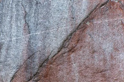 Close-up of a textured rock surface with a mix of gray and reddish-brown hu.. 스톡 사진