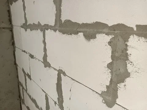 Close-up of a textured wall made of white bricks with visible mortar joints.. 库存照片