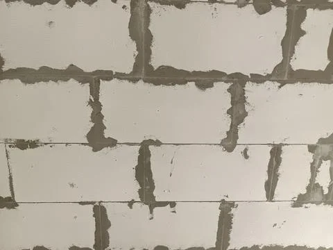 Close-up of a textured wall made of white bricks with visible mortar joints.. 库存照片