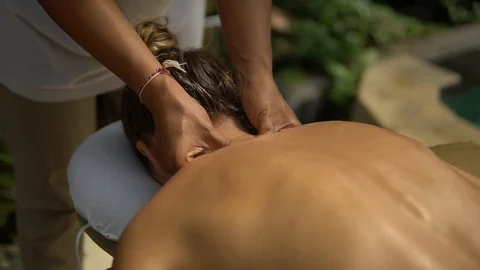 Close-up Thai masseuse makes neck massage in spa outside area for young client Stock Footage 108028529