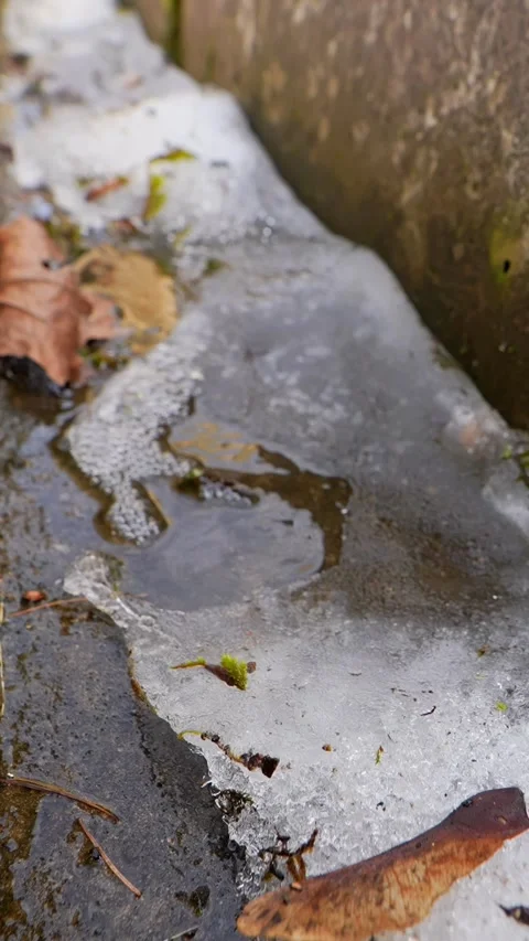 Close-up of thawing ice beside a stone edge, capturing frozen texture Stock Footage 333655884