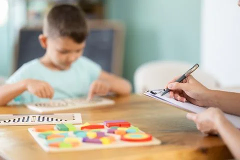 Close-up of therapist hands taking notes during child labyrinth assessment Stock Photos